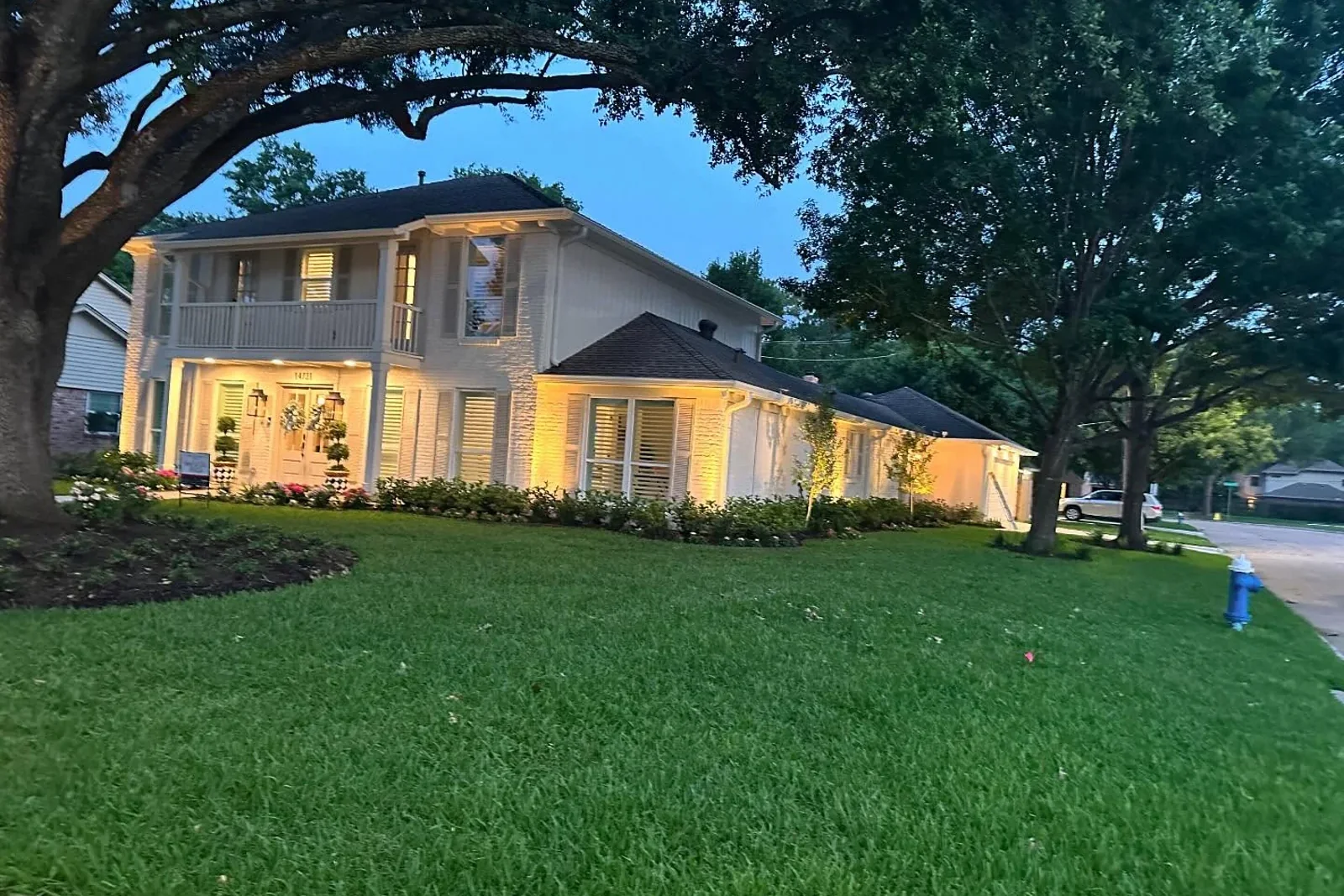 A home at dusk with warm landscape lighting washing the front